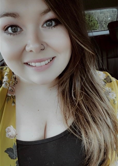 A young woman with light brown hair smiles for a selfie