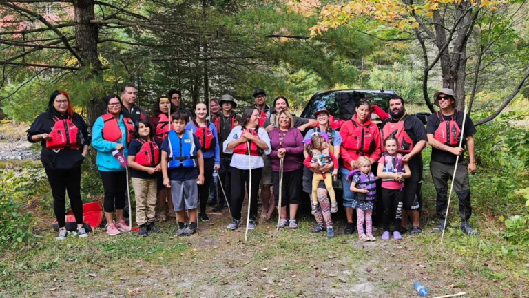 A group of people wearing life jackets standing in nature smiling