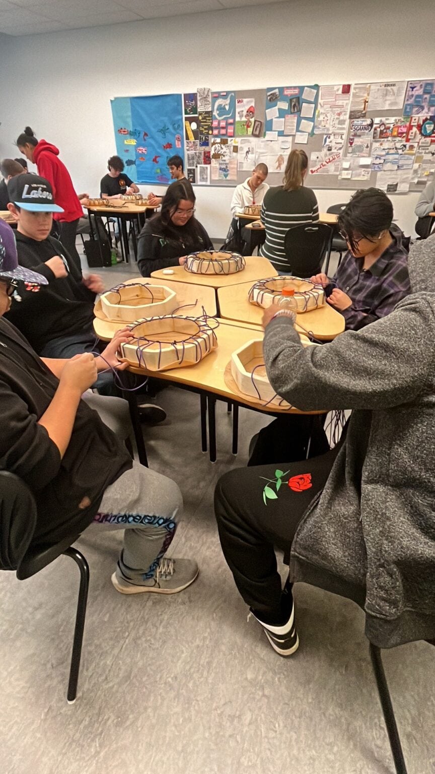 Youth gathered around a table making drums